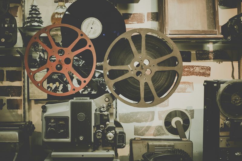 A vintage film projector with two reels against a brick wall